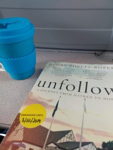 a picture of unfollow by megan phelps roper on a train table with a blue portable tea cup next to it